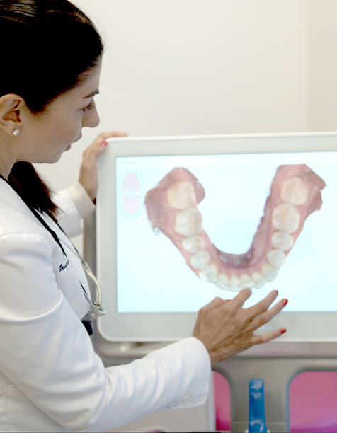 Dr Sheena Sood looking at a 3D image of a patient's teeth on screen.