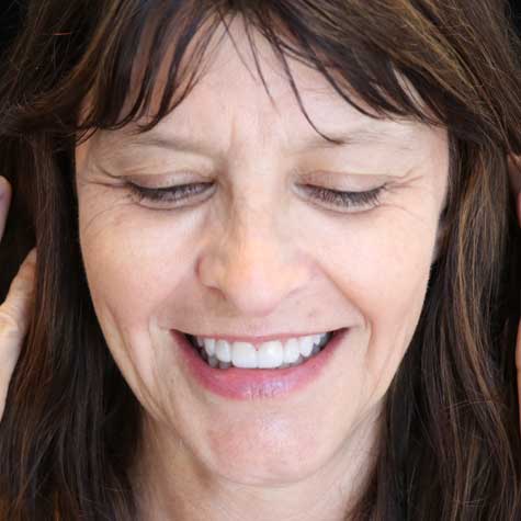 A Digital Smile Design patient smiling and looking down at the floor.